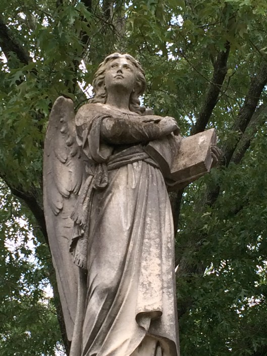 Holding what looks to be an open Bible, this angel has an almost defiant look on her face as she gazes Heavenward.